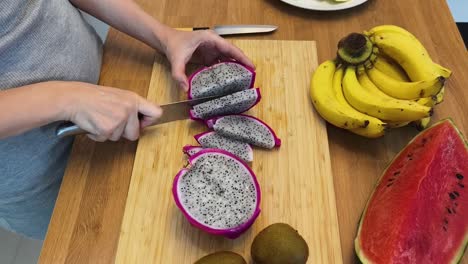 preparando un plato de frutas con frutas del dragón, plátanos, sandía y kiwi