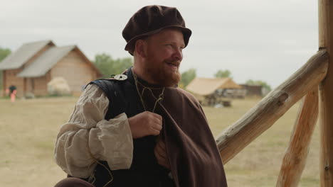 bearded squire laughs and chats holding bottle in bosom