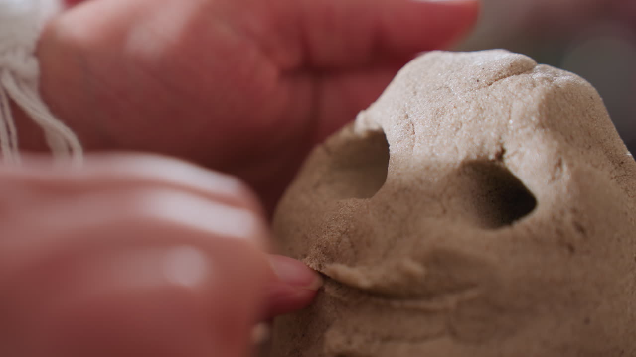 Visitor carefully sculpts mouth on octopus mold using finger during sensory therapy session, highlighting tactile engagement and creative expression with blurred background of person in blue gown