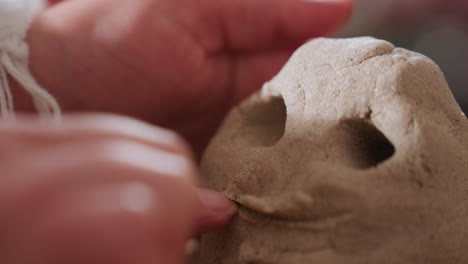 visitor carefully sculpts mouth on octopus mold using finger during sensory therapy session, highlighting tactile engagement and creative expression with blurred background of person in blue gown