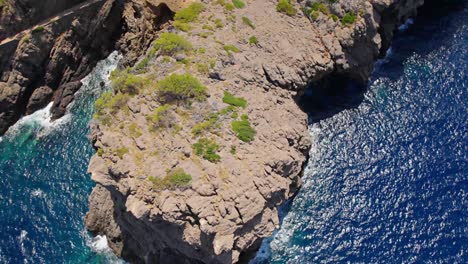 revealing drone shot of a rough cliff bay with yacht´s anchor and mountain´s in the backround