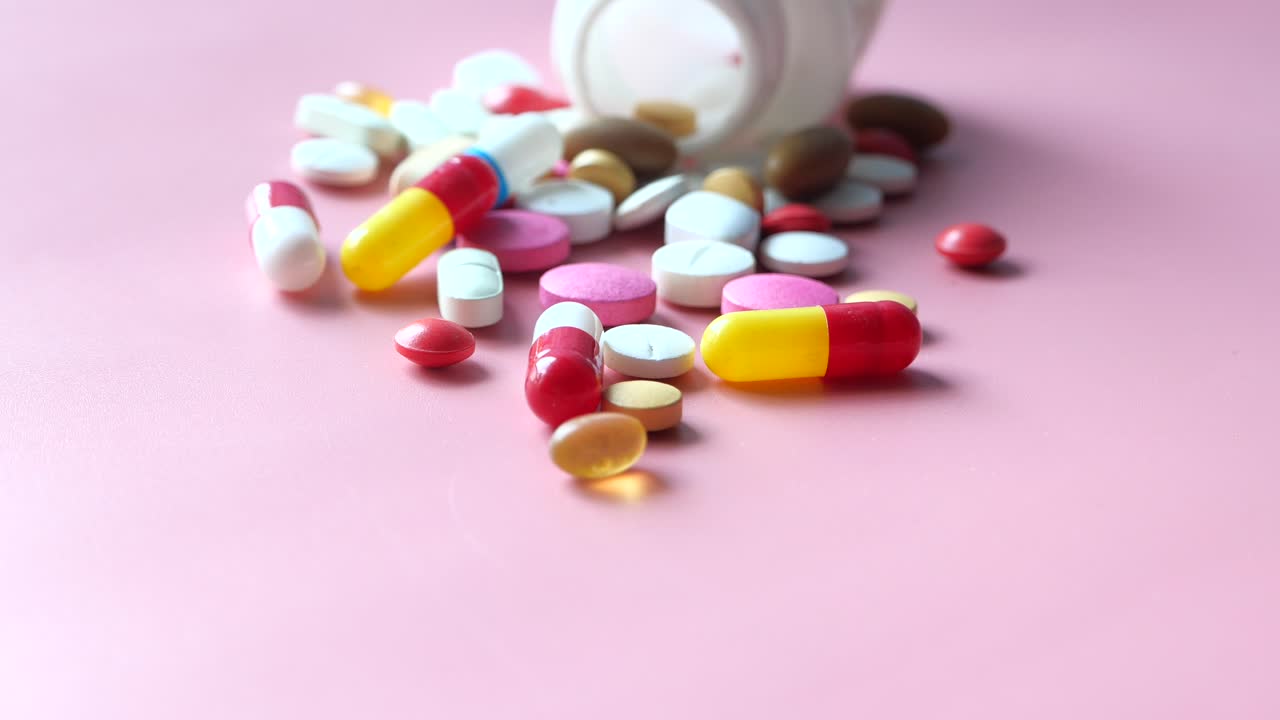 pastillas y cápsulas variadas sobre un fondo rosado