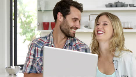 una pareja bonita de pie mirando su portátil