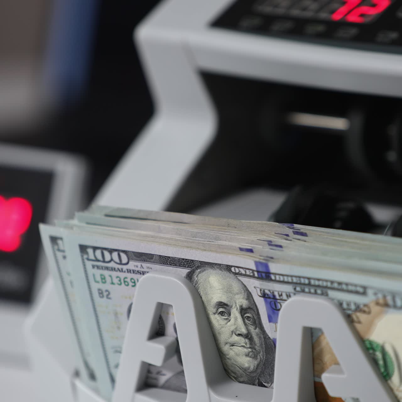 Switched on money counting machine. Hundred dollar bills turning in the counting mechanism. Close up