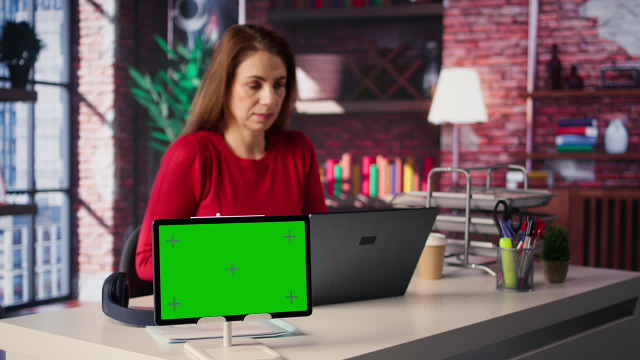 Woman working in office with tablet with green screen