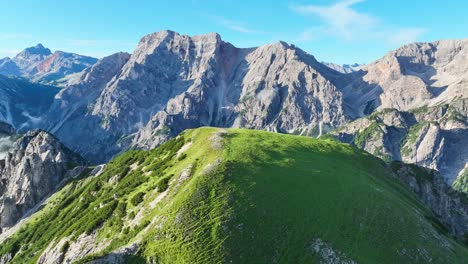 Scenic-summer-aerial-view-of-a-green-hill-in-the-foreground-and-the-jagged-Seekofel-mountain-peak-in-the-background-in-Italy's-Dolomite-mountain-range-during-the-day
