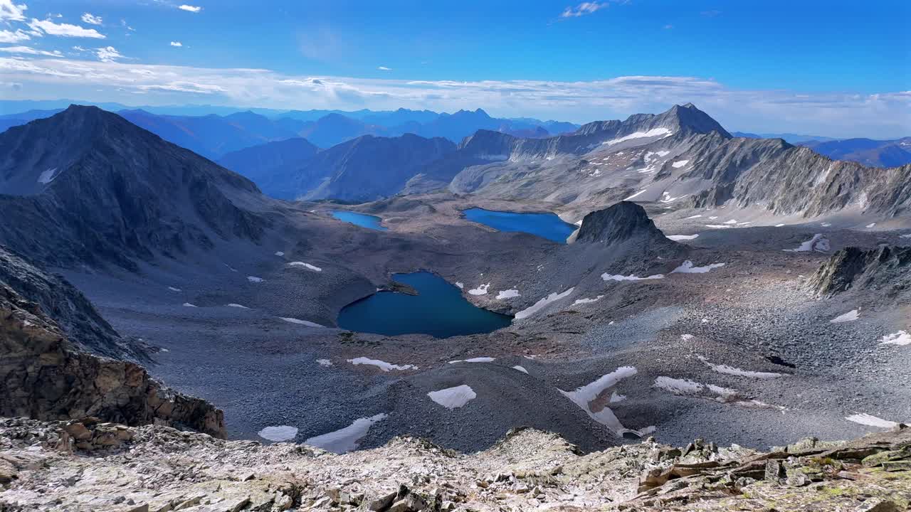 Capitol Peak 14er Wilderness high alpine elevation Rocky Mountains Colorado aerial drone Maroon Bells Peaks Mount Snowmass Pierre Lakes summer early morning blue sky clouds Knifes Edge Ridge pan left
