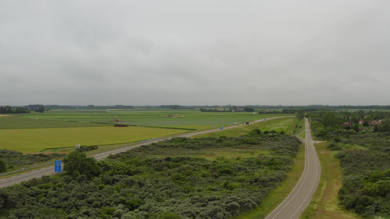 흐린 여름날 네덜란드 zeeland의 walcheren 반도에 있는 농지를 통과하는 풍력 터빈과 도로의 공중 촬영