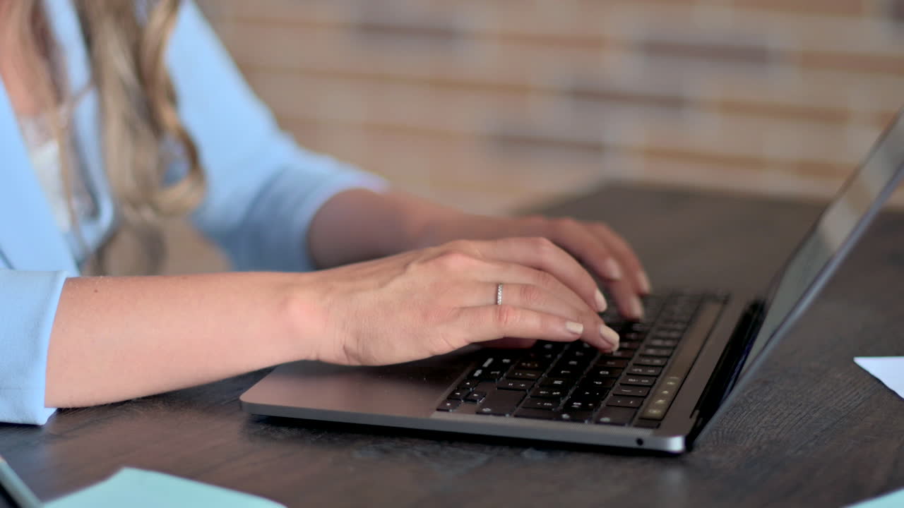 Woman in blue blazer typing on a laptop at a desk in an office