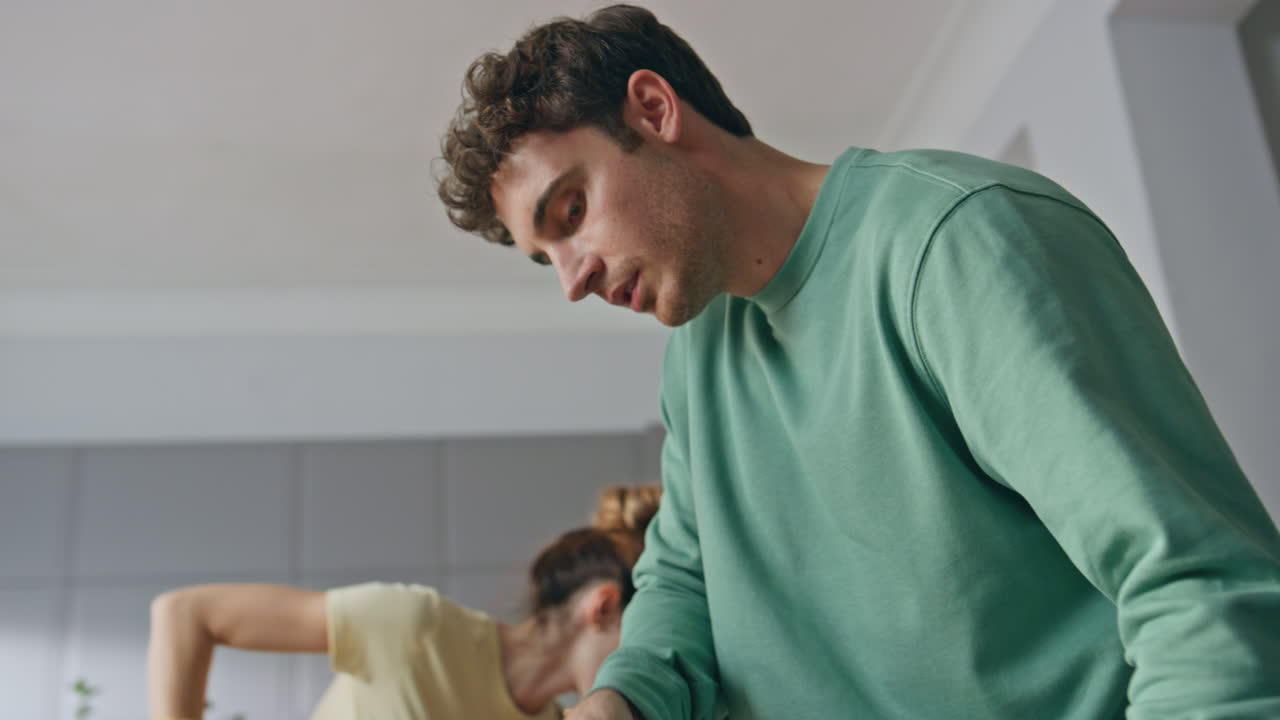 Closeup couple cleaning home together. Young pair using mop and vacuum cleaner