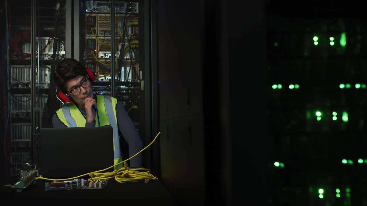 técnico asiático con auriculares usando una computadora portátil y comprobando el servidor de la computadora