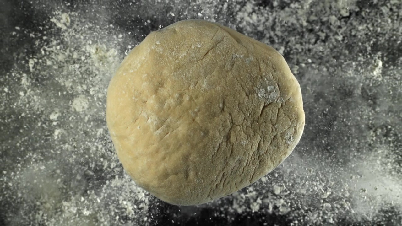 Fresh Ball of Dough with Flour Dusting on Dark Surface