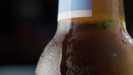 close-up of a chilled beer bottle with condensation, dark background