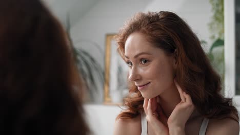 Redhead-caucasian-woman-in-the-bathroom-checking-face-condition.