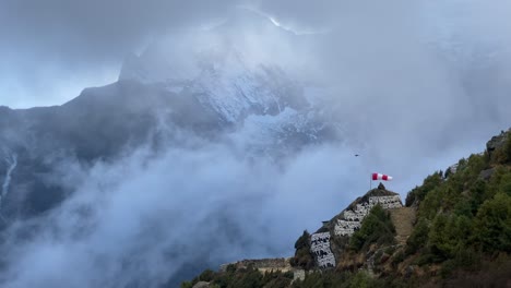 una hermosa vista de las nubes subiendo por un valle con una montaña al fondo y una manga de viento y una plataforma para helicópteros en primer plano