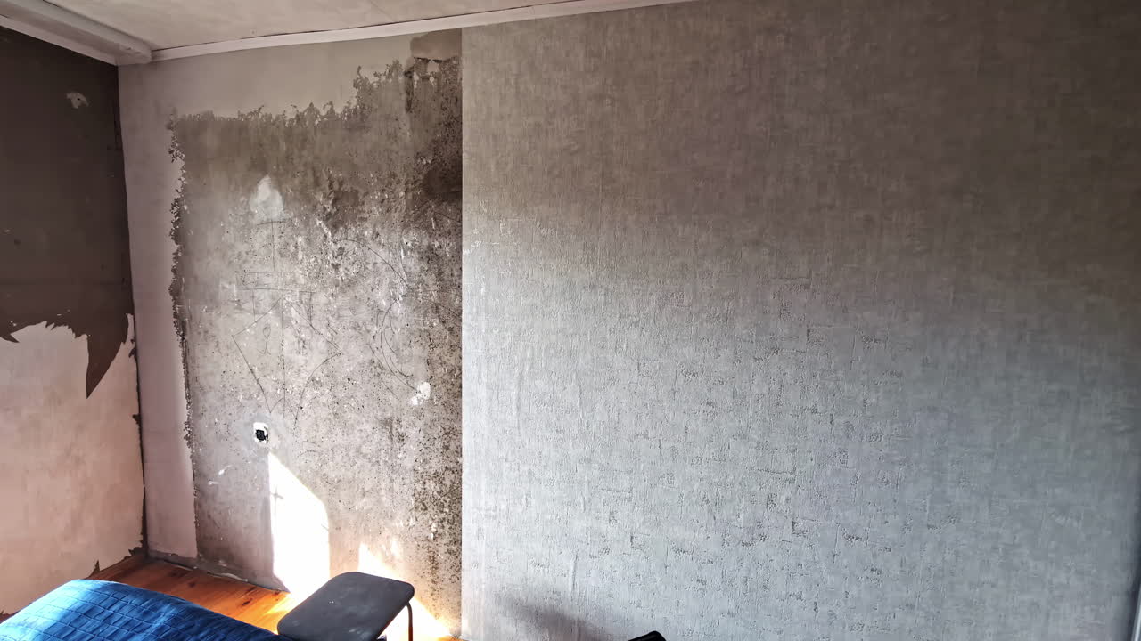 Wall being covered with new grey wallpaper in interior remodel