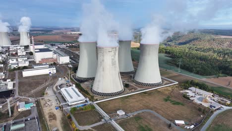 aerial view of nuclear power plant cooling towers emit white smoke in atmosphere