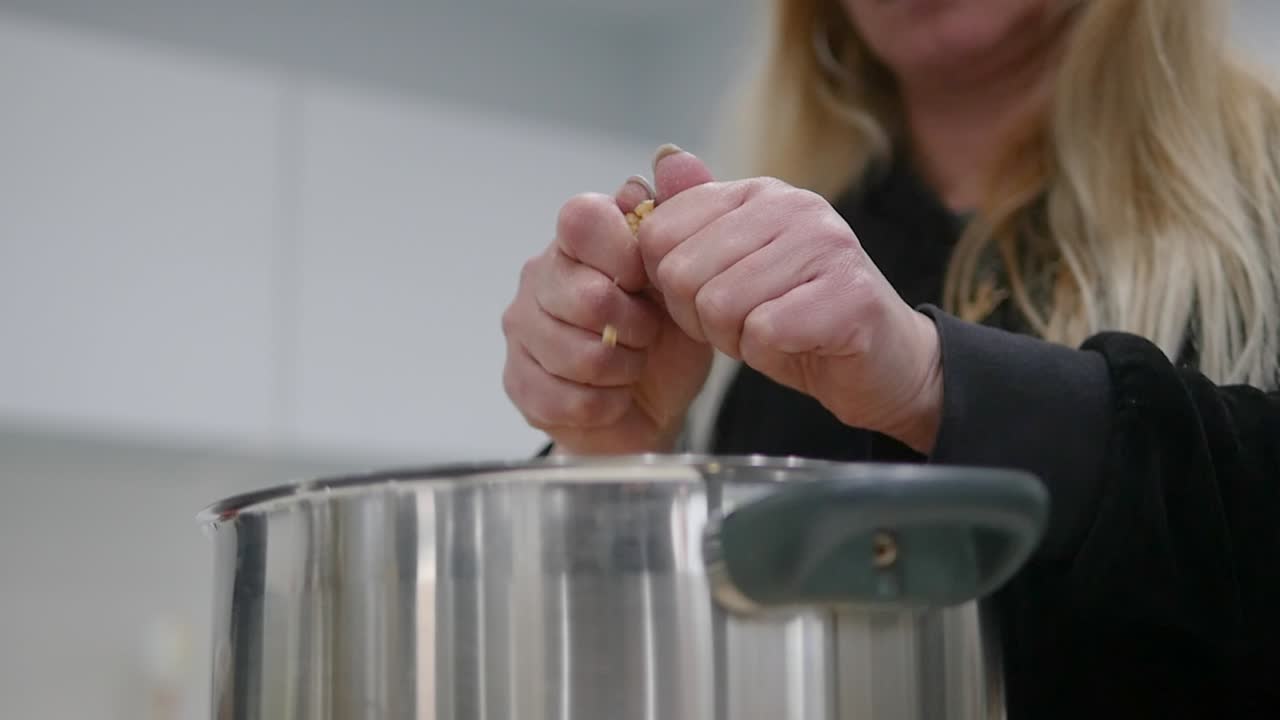 sobre la foto de una mujer cortando pedazos de trahana en una olla grande usando sus manos