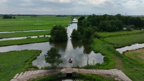 Wunderschöne-Filmische-Luftdrohne,-Die-Menschen-In-Einem-Kleinen-Boot-Auf-Einem-Holländischen-Polder-Folgt