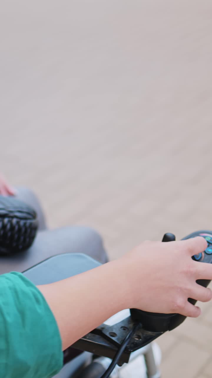 Mano di una persona che aziona il joystick di una sedia a rotelle elettrica.