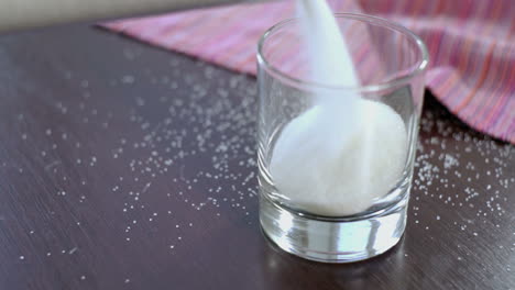 Pouring-sugar-in-glass-container-prepare-for-baking.-Closeup-of-glass-with-sugar