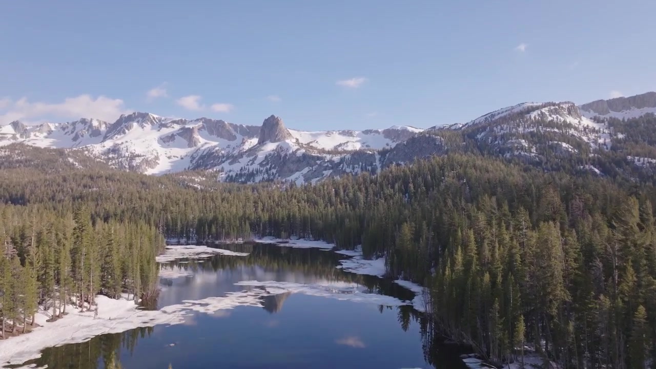 Fredelig fjellandskap sett fra drone ved Twin Lakes i Mammoth Lakes, California, med fokus på den tette furuskogen, robuste alpine skråninger og det rolige bresjøbassenget under klart vær