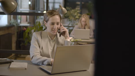 mujer de negocios hablando por teléfono móvil y trabajando en una computadora portátil en la oficina