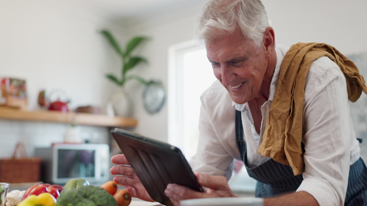 hombre mayor usando tableta para cocinar receta en la cocina