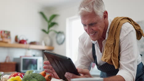 hombre mayor usando tableta para cocinar receta en la cocina