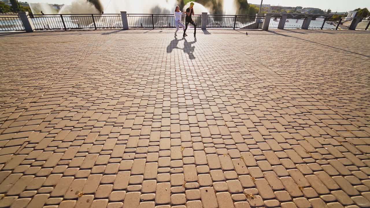 Modern dancers are dancing in the street. Urban lifestyle. Hip-hop generation. Boy's and girl's emotional moves on the video. Paving stones and young dacing couple at fontain background. Aerial view. Young beauty dances behind handsome boy.