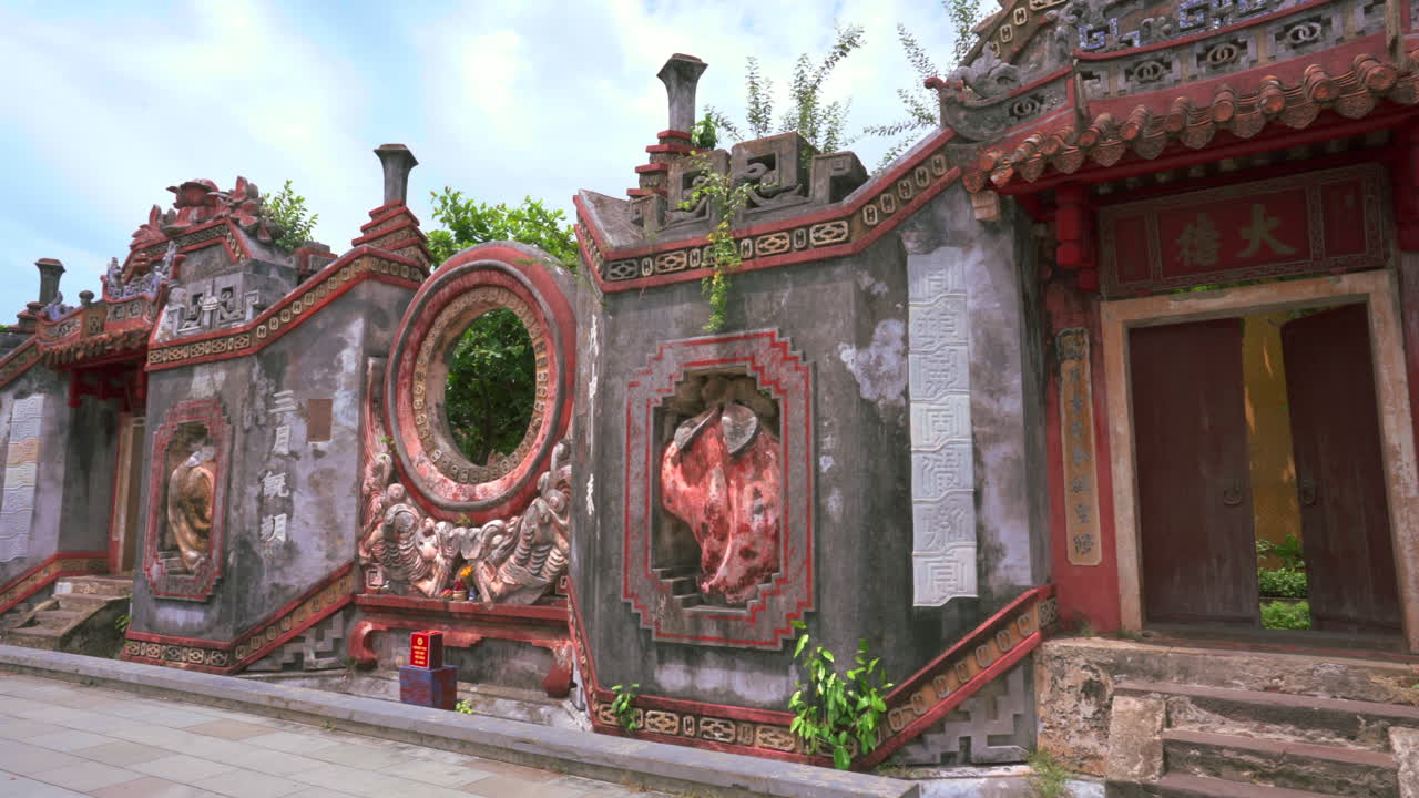 Weathered pink Chinese temple door with carvings in Hoi An, Vietnam, dappled sunlight, establishing pan