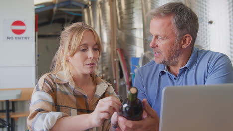 workers with laptop meeting checking production inside winery with storage tanks