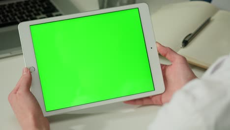 persona que sostiene la tableta con pantalla verde
