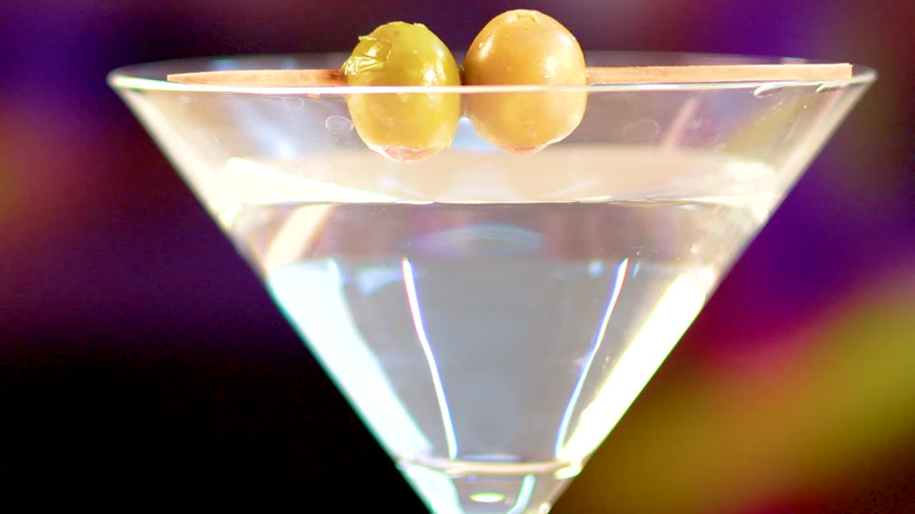 Primo piano centrato di un cocktail martini trasparente, guarnito con due olive su uno stuzzicadenti