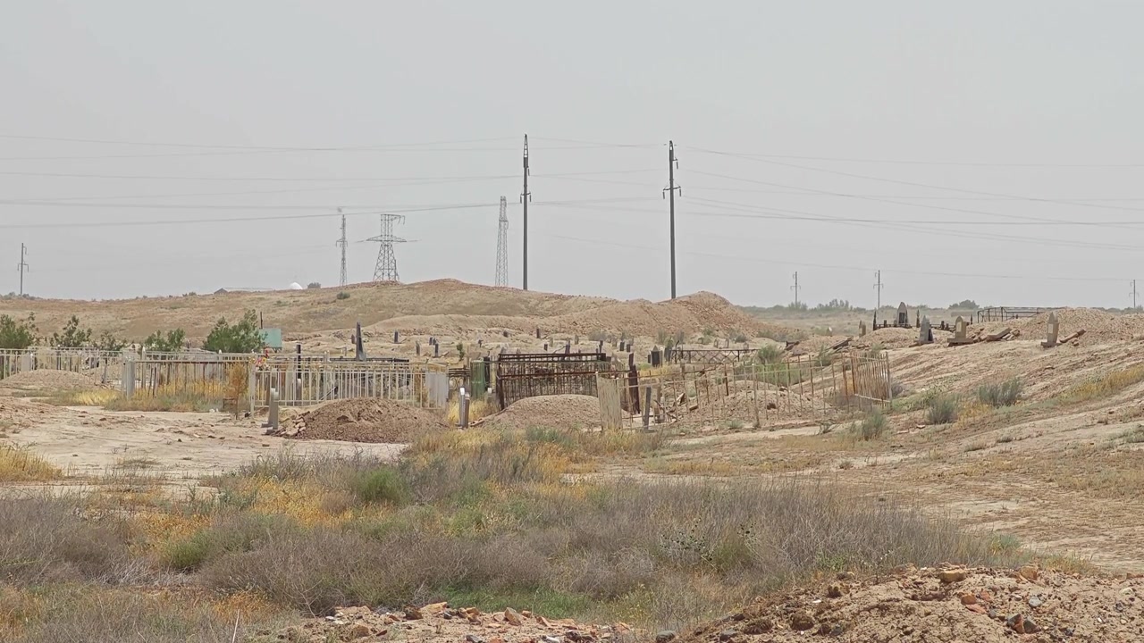 Vecchio cimitero in un paesaggio arido con linee elettriche.