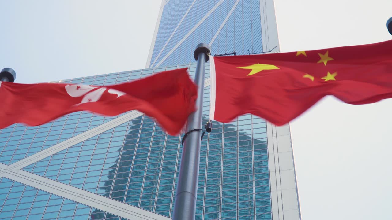 Bandeira de Hong Kong tremulando ao lado da bandeira da China em um distrito financeiro central