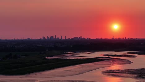 stunning view, orange and red sky over rotterdam and the calm water of the river noord