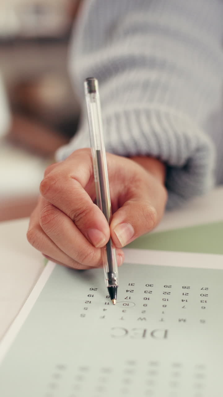 Nærbillede af hånd, der laver cirkel om dato i december kalender med pen
