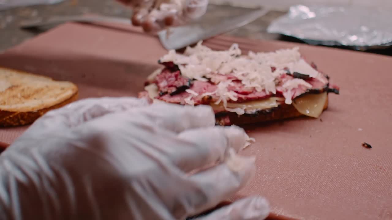 Preparazione di un panino al pastrami, carne e pane, primo piano.