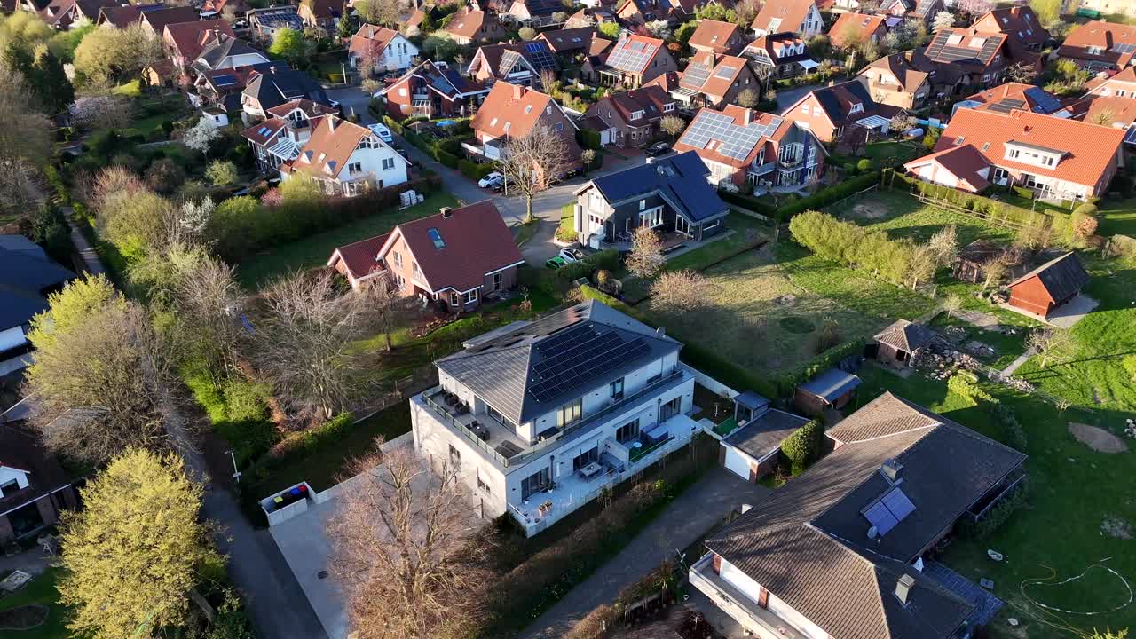 Solar panels on roof of high class residential apartment during sunset time. Aerial top down flyover shot. Suburb district in spring season. Spring season with green grass in garden. Quiet