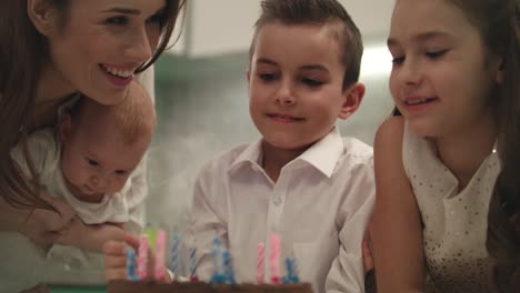 Happy-family-birthday-party-at-home.-Family-blowing-candle-flames-on-party-cake