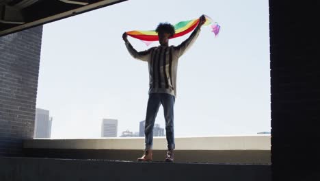 Afroamerikanischer-Mann-Hält-Lbgt-Flagge,-Während-Er-Am-Fenster-Steht