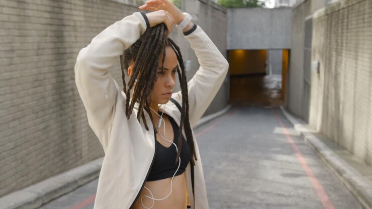 Vista laterale di una giovane donna afroamericana che si lega i capelli raccolti in città 4k