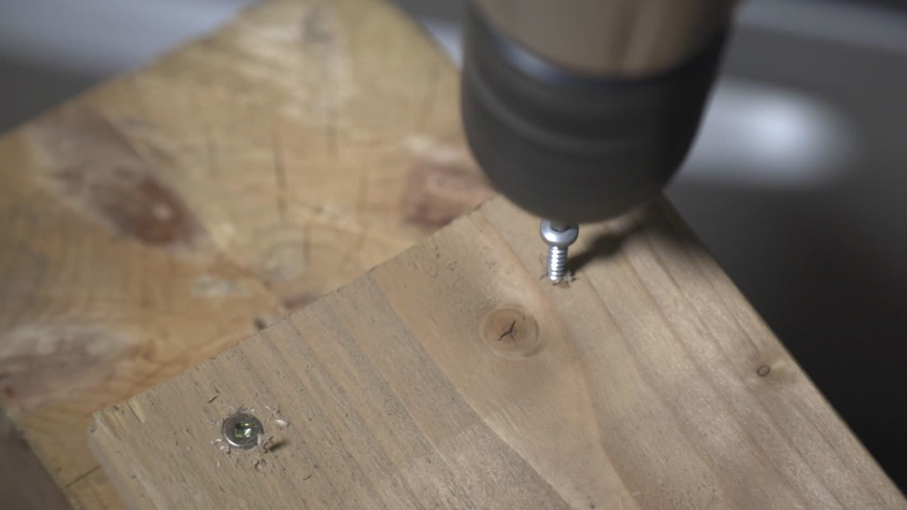A Carpenter Using Electric Drill To Screwing Pieces Of A Wooden Board. - close up shot