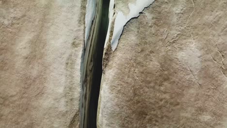 aerial top view over an ice crevasse, cracked on the ice surface of an icelandic glacier, on a sunny day