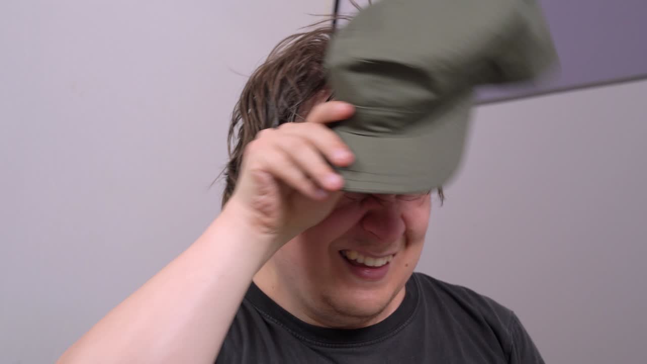 야구 모자를 입은 남자는 그것을 벗고, 이마와 머리에서 을 고, 다시 모자를 착용합니다. 열심히 일하는 개념, 망진창의 머리카락, 피곤한 얼굴 표정.