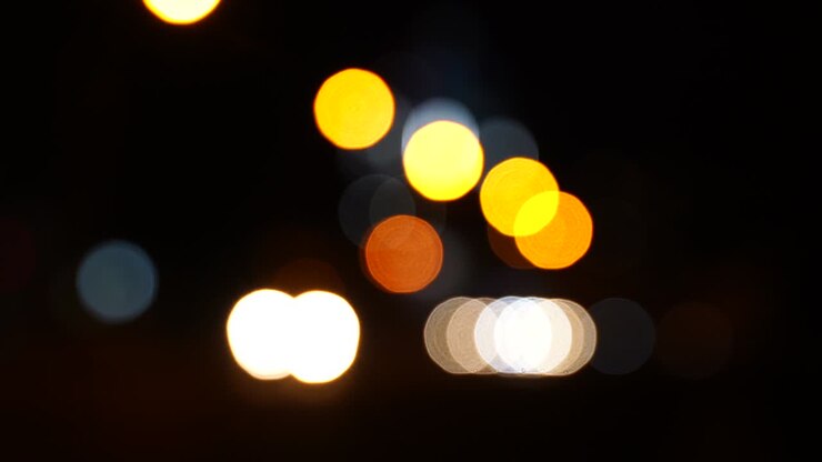 Traffico notturno sfocato con bokeh su strada in una grande città.