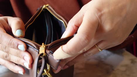 close-up of a woman opening a brown leather purse