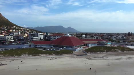 toma de dron de la playa de muizenberg, ciudad del cabo - dron está retrocediendo desde una casa, revelando la playa y el océano