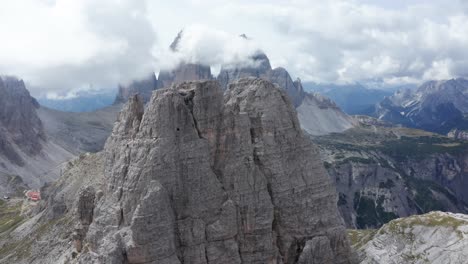 Mountain-climber-descending-tall-mountain-peak-in-Italian-Dolomites,-Tre-Cime,-aerial-dolly-in